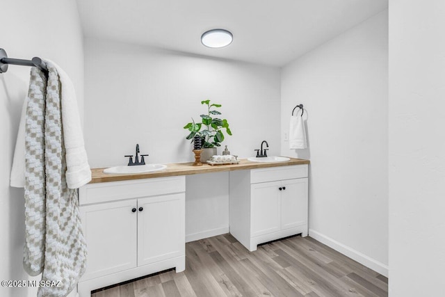 full bathroom featuring double vanity, baseboards, a sink, and wood finished floors