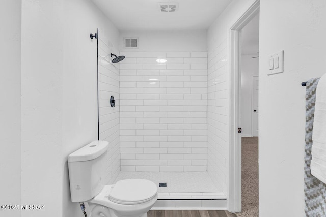 bathroom featuring toilet, a shower stall, and visible vents