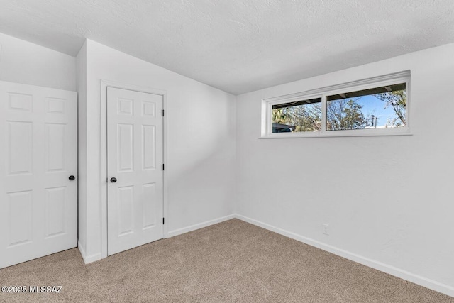 unfurnished bedroom featuring a textured ceiling, baseboards, and carpet flooring