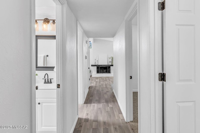 hallway with a sink, baseboards, and wood finished floors