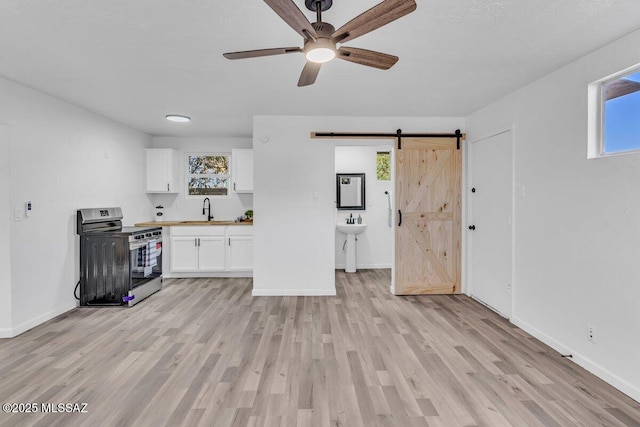 interior space featuring a barn door, a sink, white cabinetry, light wood-style floors, and stainless steel electric range