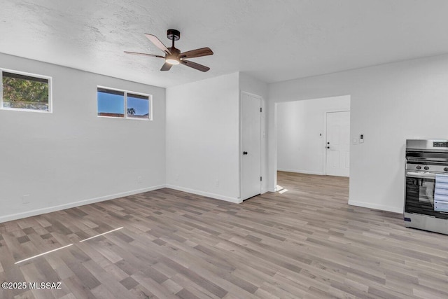 unfurnished living room featuring ceiling fan, light wood-style flooring, baseboards, and a textured ceiling