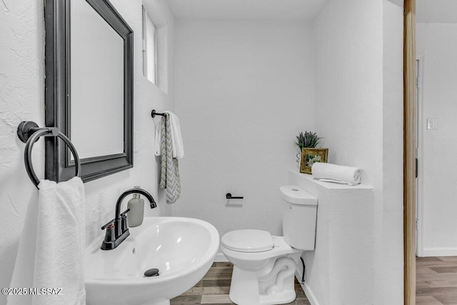 bathroom with toilet, baseboards, a sink, and wood finished floors