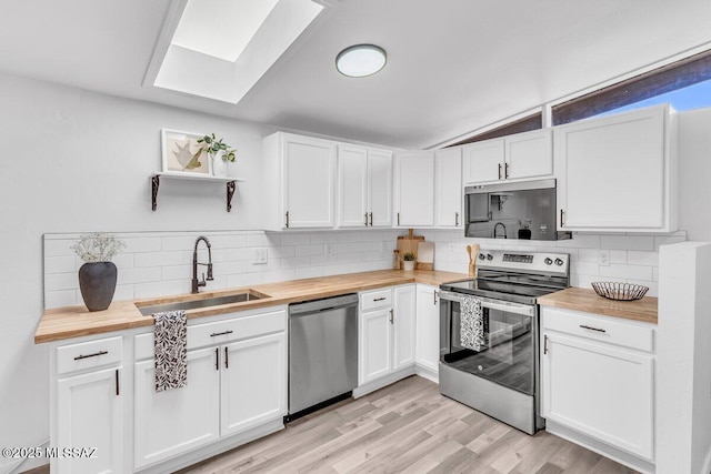 kitchen featuring open shelves, stainless steel appliances, white cabinets, a sink, and butcher block countertops