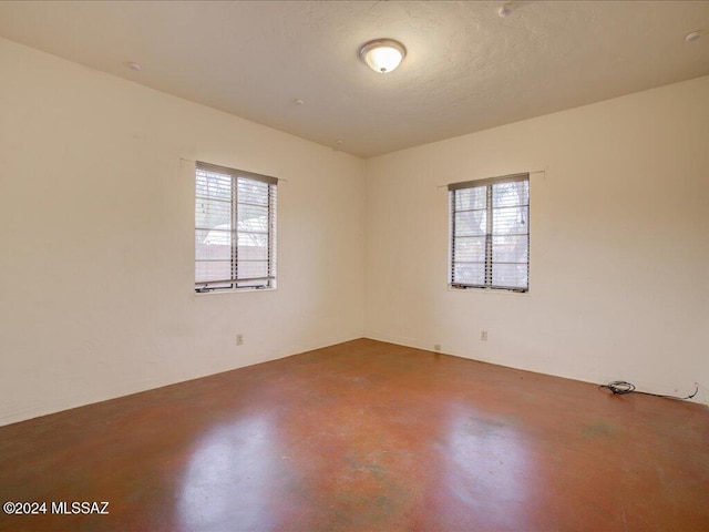 empty room featuring a wealth of natural light, concrete floors, and a textured ceiling