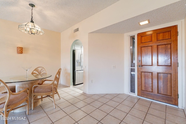 dining area featuring a notable chandelier, a textured ceiling, and light tile patterned floors