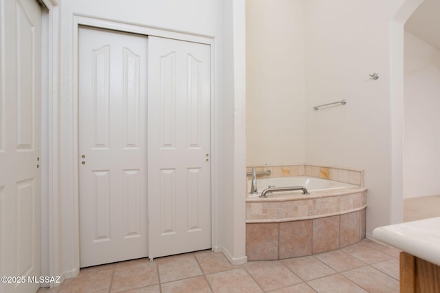 bathroom with a relaxing tiled tub and tile patterned floors