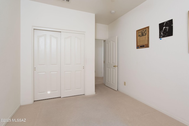 unfurnished bedroom with light colored carpet and a closet