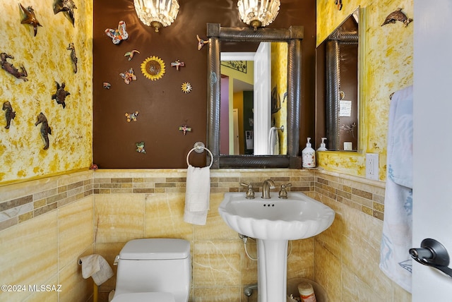 bathroom featuring an inviting chandelier, tile walls, and toilet