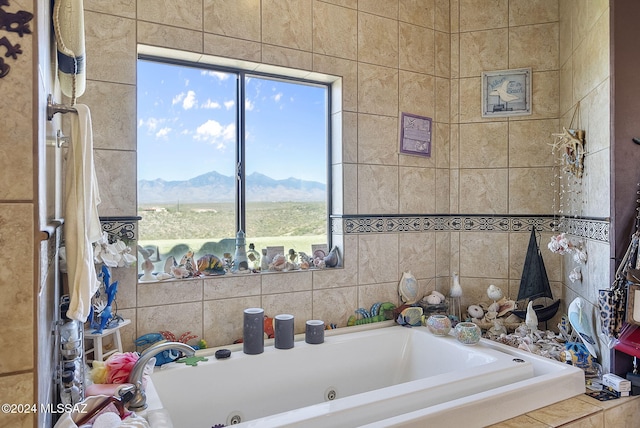 bathroom featuring tiled bath, tile walls, and a mountain view