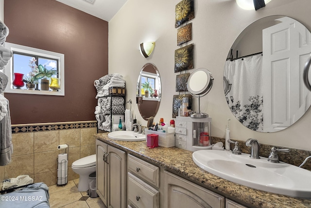 bathroom with vanity, toilet, tile patterned floors, and tile walls