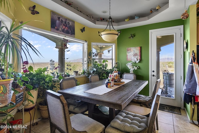 tiled dining area with a tray ceiling