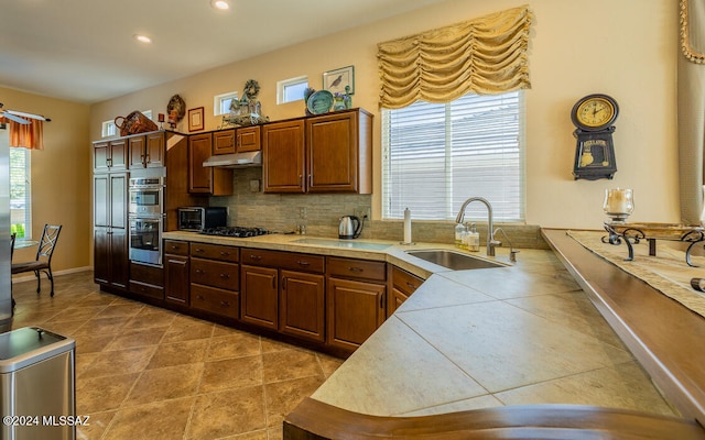 kitchen featuring sink, backsplash, double oven, black gas cooktop, and tile counters