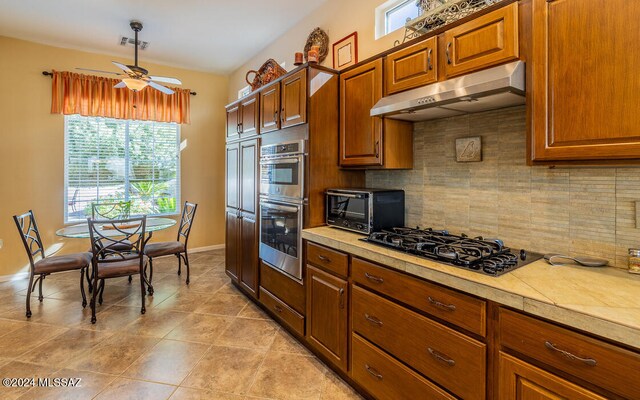 kitchen featuring black gas stovetop, tasteful backsplash, double oven, and ceiling fan