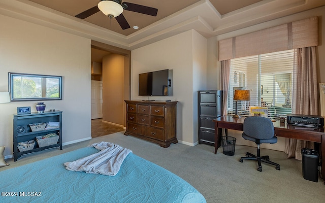 carpeted bedroom with multiple windows, a raised ceiling, and ceiling fan