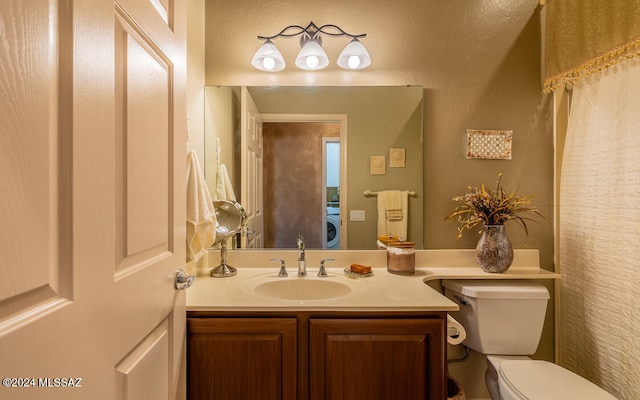 bathroom featuring vanity, washer / clothes dryer, and toilet