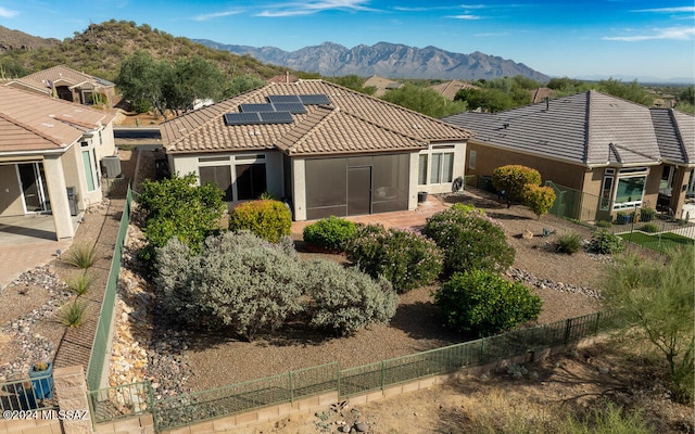 back of house with solar panels, a mountain view, and a patio