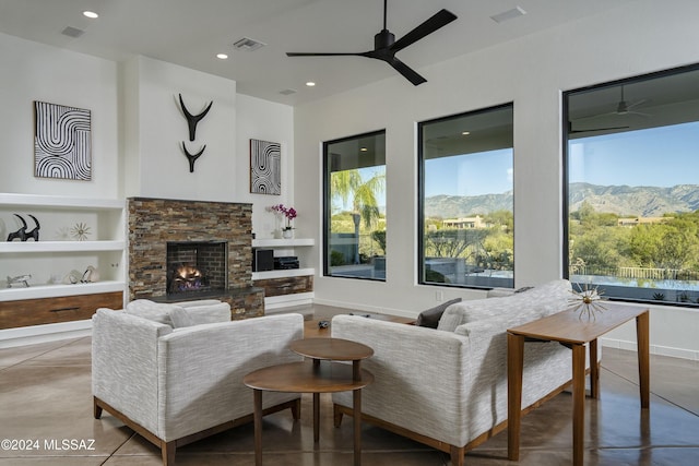 living room featuring ceiling fan, a fireplace, a mountain view, and built in features