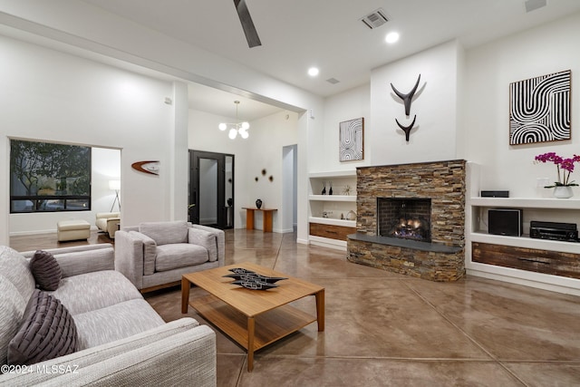 living room with a fireplace, concrete floors, a chandelier, a high ceiling, and built in shelves