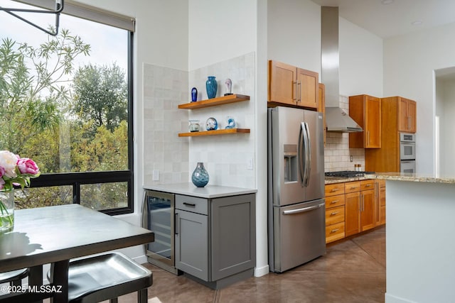 kitchen featuring gray cabinets, stainless steel appliances, tasteful backsplash, light stone countertops, and beverage cooler