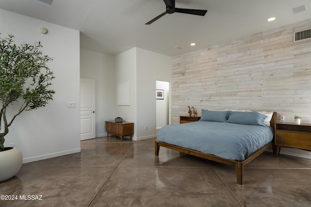 bedroom featuring concrete floors, ceiling fan, and wood walls