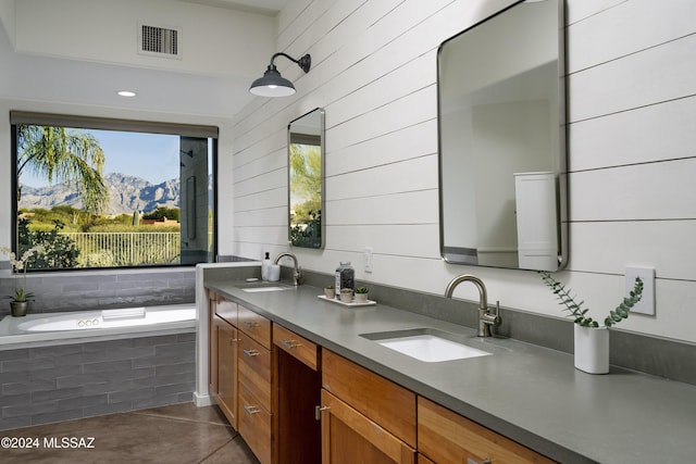 bathroom featuring a relaxing tiled tub, a mountain view, and vanity