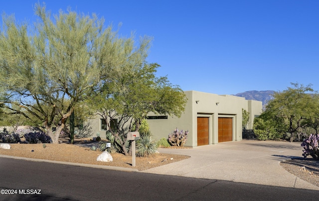 pueblo-style home with a garage and a mountain view