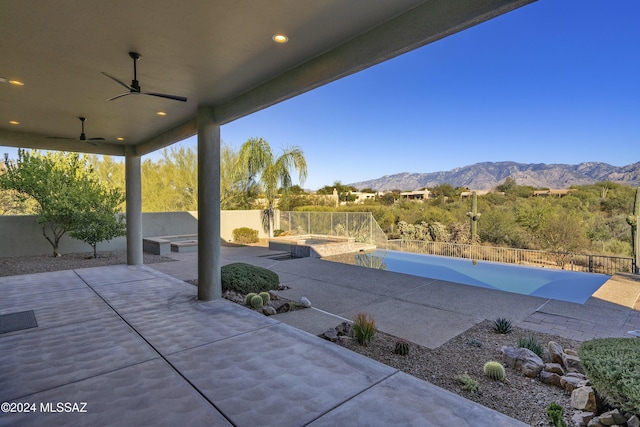 view of patio / terrace featuring a fenced in pool, ceiling fan, and a mountain view