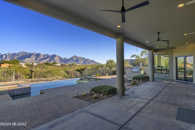 view of patio with area for grilling, a mountain view, a fenced in pool, and ceiling fan