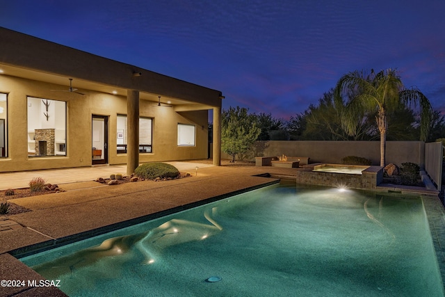 pool at dusk featuring an in ground hot tub, ceiling fan, and a patio