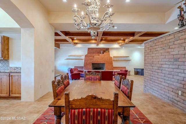 tiled dining area with coffered ceiling, a large fireplace, a notable chandelier, and brick wall