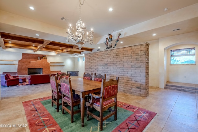 tiled dining space with beamed ceiling, a notable chandelier, a large fireplace, and coffered ceiling