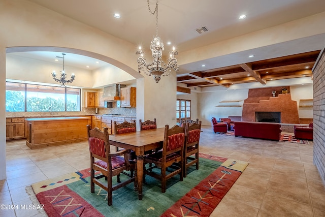 dining area with coffered ceiling, beamed ceiling, a chandelier, a fireplace, and light tile patterned floors