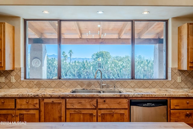 kitchen with dishwasher, backsplash, light stone countertops, and sink