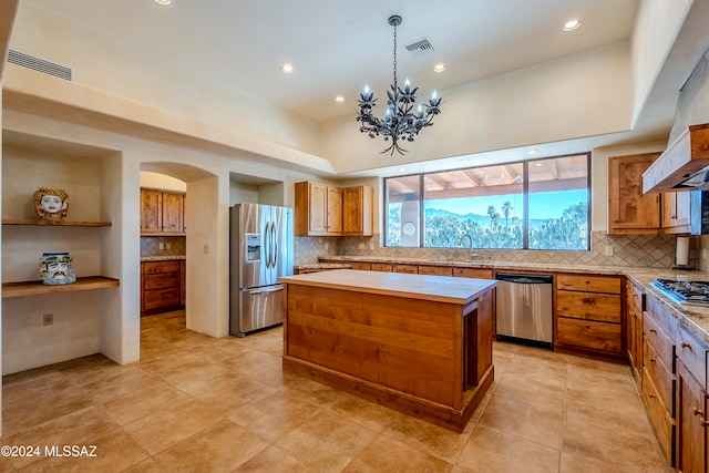 kitchen with backsplash, a center island, a chandelier, and appliances with stainless steel finishes