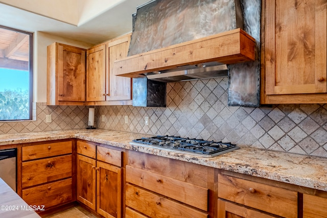 kitchen featuring premium range hood, light stone counters, tasteful backsplash, and appliances with stainless steel finishes