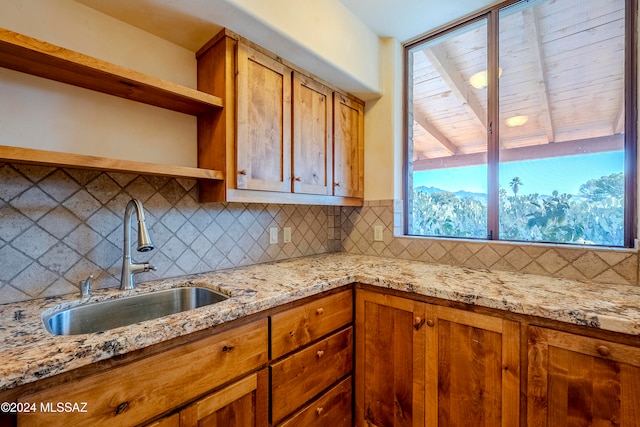 kitchen with light stone countertops, tasteful backsplash, and sink