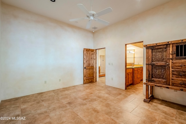 tiled bedroom with ceiling fan, a high ceiling, and ensuite bath