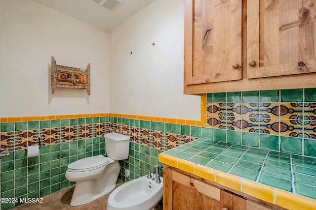 bathroom with tile patterned flooring, toilet, tile walls, and a bidet