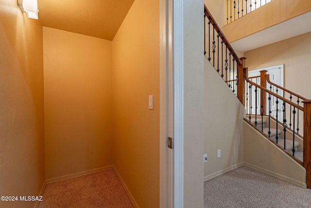 stairway featuring lofted ceiling and carpet flooring