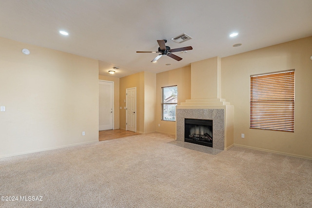 unfurnished living room featuring light carpet, a fireplace, and ceiling fan