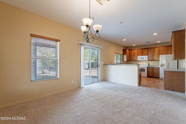 kitchen featuring white appliances, kitchen peninsula, hanging light fixtures, light carpet, and an inviting chandelier