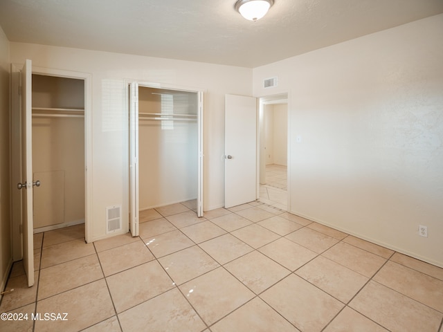 unfurnished bedroom with multiple closets and light tile patterned floors