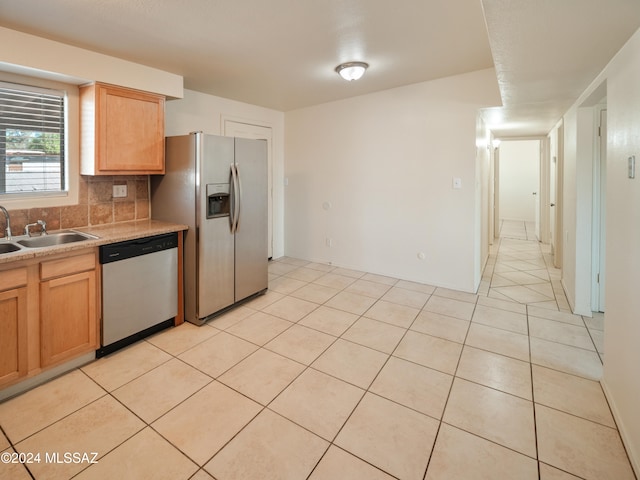 kitchen with backsplash, appliances with stainless steel finishes, sink, and light tile patterned floors