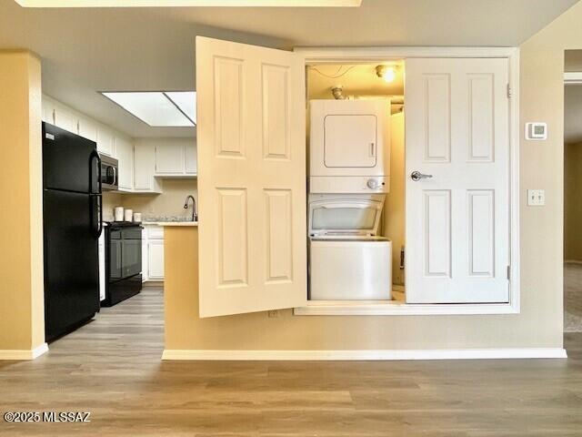 kitchen featuring stacked washer / dryer, stainless steel microwave, a skylight, freestanding refrigerator, and stove