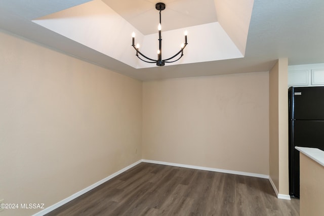 unfurnished dining area featuring dark wood finished floors, baseboards, and a chandelier