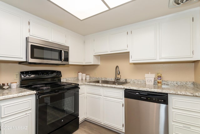 kitchen with white cabinetry, light wood finished floors, appliances with stainless steel finishes, and a sink