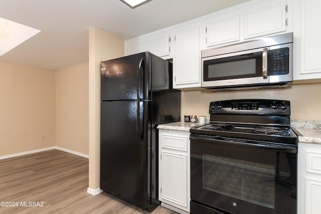 kitchen featuring light wood finished floors, baseboards, light stone countertops, white cabinets, and black appliances