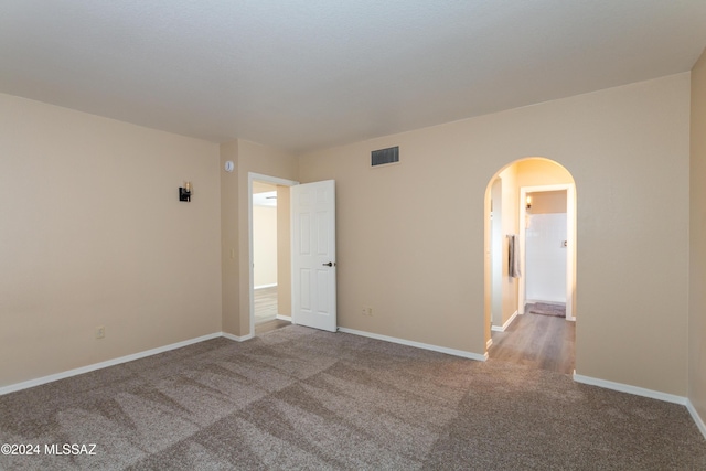 spare room with arched walkways, visible vents, baseboards, and carpet floors