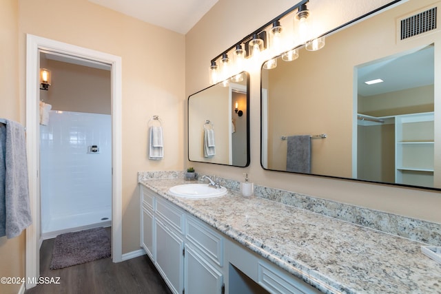 full bath featuring vanity, a shower stall, wood finished floors, and visible vents